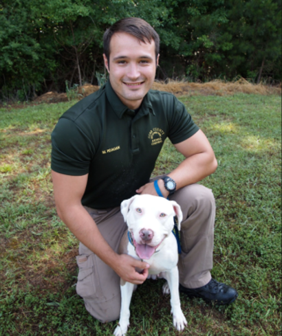 A Cobb County Animal Services employee kneeling beside a dog.